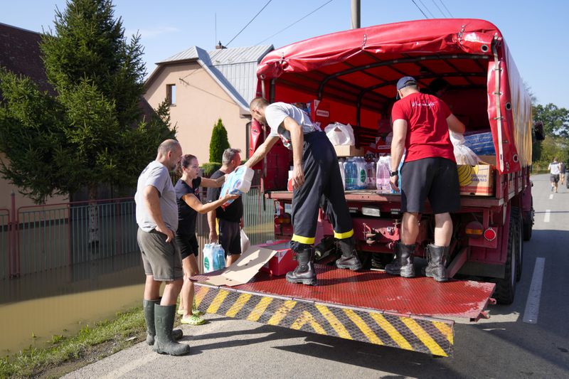 Firemen deliver aid to residents whose homes are flooded in Bohumin, Czech Republic, Tuesday, Sept. 17, 2024. (AP Photo/Darko Bandic)