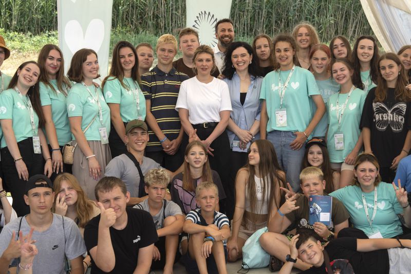 First lady Olena Zelenska, in white, poses for a photo during her visit to the rehabilitation camp "Loud Camp" for children affected by war, organized by the Voices of Children Charitable Foundation and financially supported by the Olena Zelenska Foundation in Uzhhorod, Ukraine, Tuesday, Aug. 27, 2024. (AP Photo/Efrem Lukatsky)