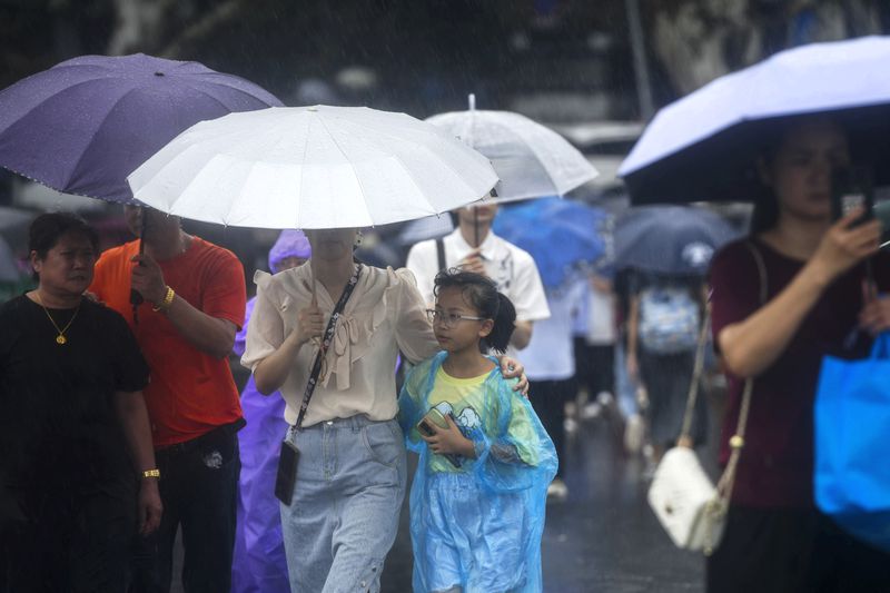 Tourists carrying umbrella tour the West Lake in the rains brought by Typhoon Bebinca during the Mid-Autumn Festival holiday, in Hangzhou in east China's Zhejiang province, Monday, Sept. 16, 2024. (Chinatopix Via AP)