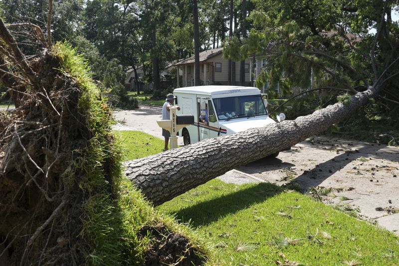 Delray Gooch, standing, talks to mail carrier Jason Phillips as he delivers mail in the aftermath of Hurricane Beryl on Wednesday, July 10, 2024, in Houston. (Jon Shapley/Houston Chronicle via AP)