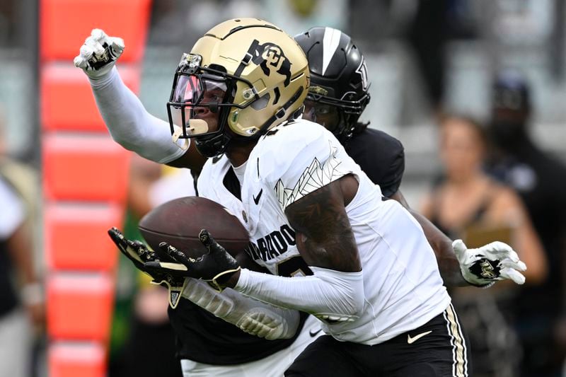 Colorado wide receiver Travis Hunter (12) catches a pass in the end zone for a 23-yard touchdown with Central Florida defensive back Brandon Adams behind him during the first half of an NCAA college football game, Saturday, Sept. 28, 2024, in Orlando, Fla. (AP Photo/Phelan M. Ebenhack)