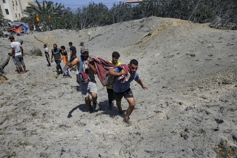 Palestinians evacuate a dead person from a site hit by an Israeli bombardment on Khan Younis, southern Gaza Strip, Saturday, July 13, 2024. Israel said it targeted Hamas’ shadowy military commander in a massive strike Saturday in the crowded southern Gaza Strip that killed at least 71 people, according to local health officials. Hamas immediately rejected the claim that Mohammed Deif was in the area. (AP Photo/Jehad Alshrafi)