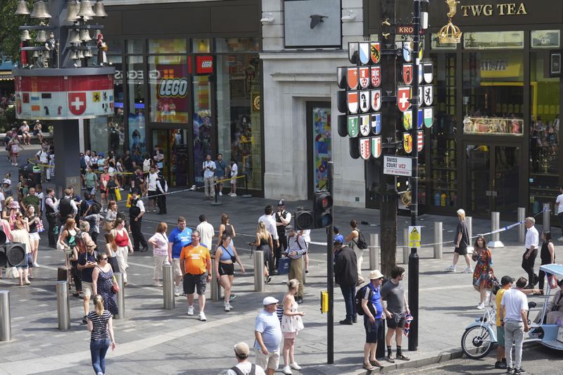 Police cordon off an area in Leicester Square, as a man was arrested with the accusation of stabbing an 11-year-old girl and 34-year-old woman, in London, Monday Aug. 12, 2024. (James Manning/PA via AP)