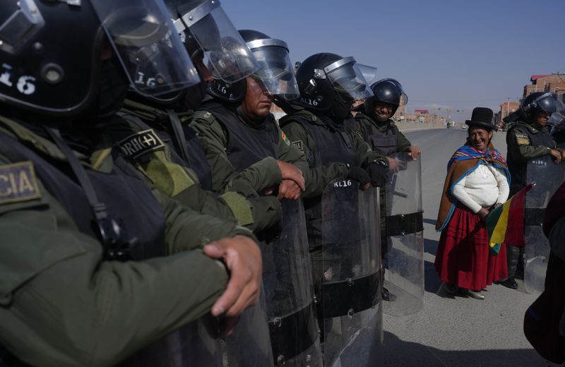 Police keep protesters from blocking more lanes as they protest for the resignation of Bolivian President Luis Arce for his management of the economy in Corapata, on the outskirts of El Alto, Bolivia, Monday, Sept. 16, 2024. (AP Photo/Juan Karita)