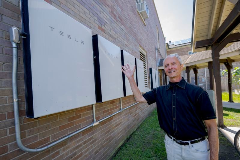 Pastor Shawn Moses Anglim poses for a photo near Tesla batteries at First Grace United Methodist Church that is part of the Community Lighthouse initiative that uses microgrids, a small-scale power system that can operate and provide electricity amid hurricanes, in New Orleans, Wednesday, Sept. 25, 2024. (AP Photo/Matthew Hinton)