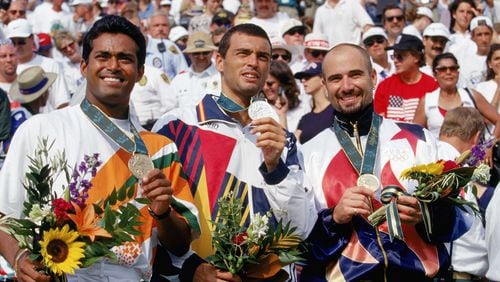 American tennis star Andre Agassi celebrates after receiving his gold medal at the 1996 Olympics in Atlanta. Leander Paes of India (left) earned the bronze and Sergi Bruguera of Spain (center) took the silver medal. (Photo by Gary M. Prior/Getty Images)