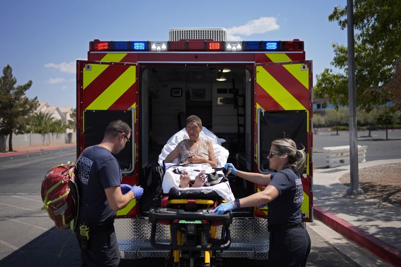 Members of the Henderson Fire Department load Deb Billet, 66, into an ambulance before transporting her to the hospital for heat-related symptoms, Wednesday, July 10, 2024, in Henderson, Nev. Billet has been living on the streets. (AP Photo/John Locher)