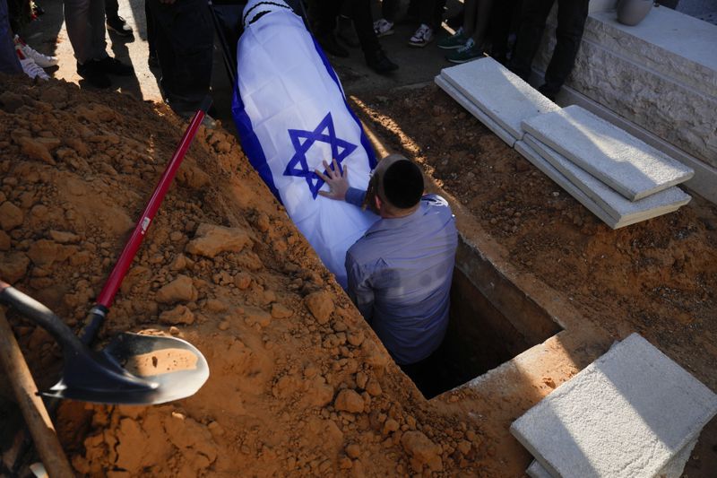 The coffin of the slain hostage Almog Sarusi, who was killed in Hamas captivity in the Gaza Strip, is placed in a grave during his funeral at a cemetery in Ra'anana, Israel, Sunday, Sept. 1, 2024. (AP Photo/Ariel Schalit)