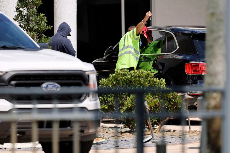 Workers attempt to gain access to a Bentley SUV in the driveway at Sean Kingston's Southwest Ranches, Fla., home on Thursday, May 23, 2024. A SWAT team raided rapper Kingston's rented mansion on Thursday, and arrested his mother on fraud and theft charges that an attorney says stems partly from the installation of a massive TV at the home. Broward County detectives arrested Janice Turner, 61, at the home. (Amy Beth Bennett/South Florida Sun-Sentinel via AP)