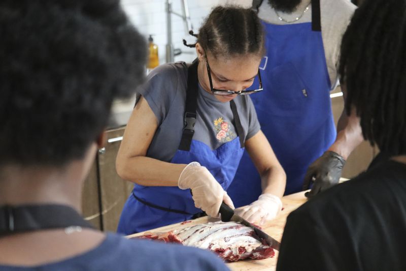 A George Westinghouse Career and Technical Education High School student participates in a butchery class at Essex Kitchen in New York, Tuesday, May 21, 2024. (AP Photo/James Pollard)