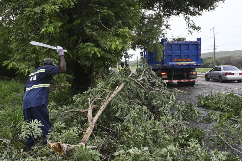 Workers remove trees branches felled by Hurricane Beryl in Kingston, Jamaica, Thursday, July 4, 2024. What had been the earliest storm to develop into a Category 5 hurricane in the Atlantic, weakened to a Category 3 by early Thursday but remained a major hurricane taking aim at Mexico’s Caribbean coast. (AP Photo/Collin Reid)