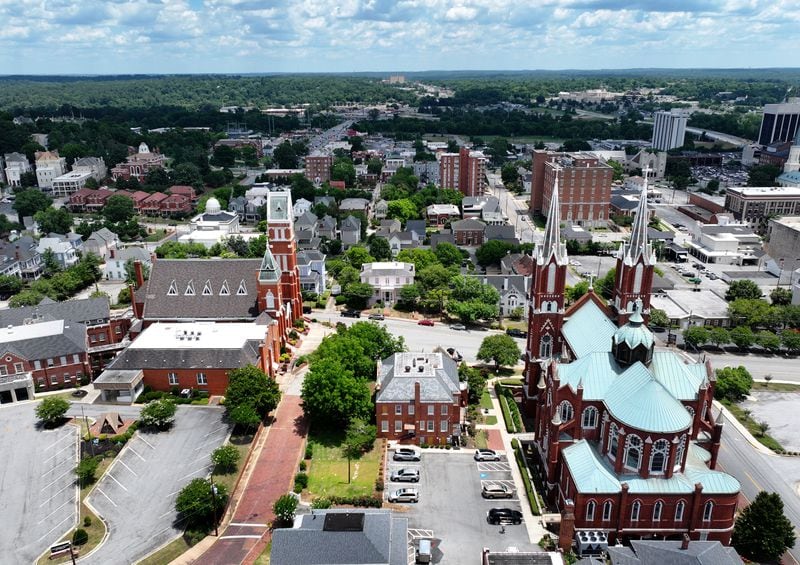 An aerial view of downtown Macon's skyline looking toward the Ocmulgee River. The view includes churches in the foreground and, at upper right, the tall, whitish-tower is the long-vacant Hilton hotel.