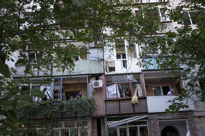 Local residents clear broken glass from their balconies after a Russian bombardment of a residential neighbourhood in Pokrovsk, Donetsk region, Ukraine, Tuesday Aug. 20, 2024. (AP Photo/Evgeniy Maloletka)