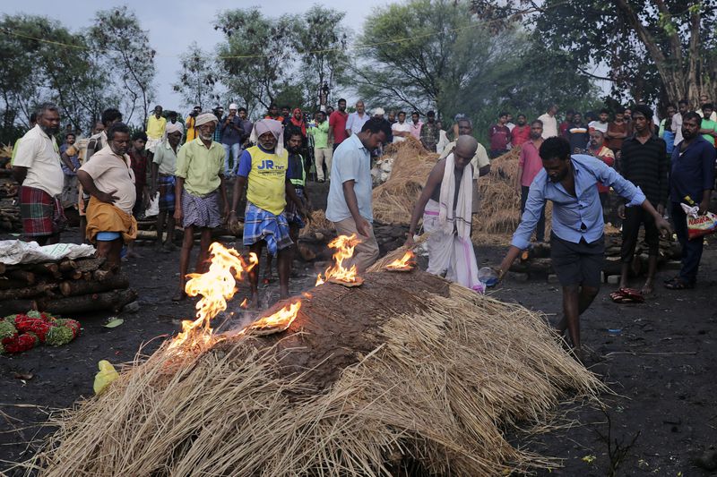 A boy with his head shaved lights the funeral pyre of his father, who died after drinking illegally brewed liquor, in Kallakurichi district of the southern Indian state of Tamil Nadu, India, Thursday, June 20, 2024. The state's chief minister M K Stalin said the 34 died after consuming liquor that was tainted with methanol, according to the Press Trust of India news agency. (AP Photo/R. Parthibhan)