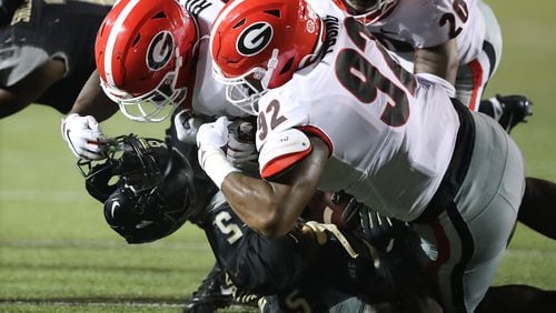 Georgia linebacker Monty Rice (L) ended up with Ke'Shawn Vaughn's helmet in his hand after he, Justin Young (92) and J.R. Reed gang-tackled Vanderbilt's star running back last Saturday. The Bulldogs will be looking for fewer penalties and more havoc in their home opener Saturday against Murray State. Curtis Compton/ccompton@ajc.com