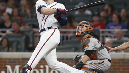 The Braves’ Adam Duvall  hits a two-run homer in the seventh inning while Giants catcher Buster Posey looks on during Saturday’s game at SunTrust Park.