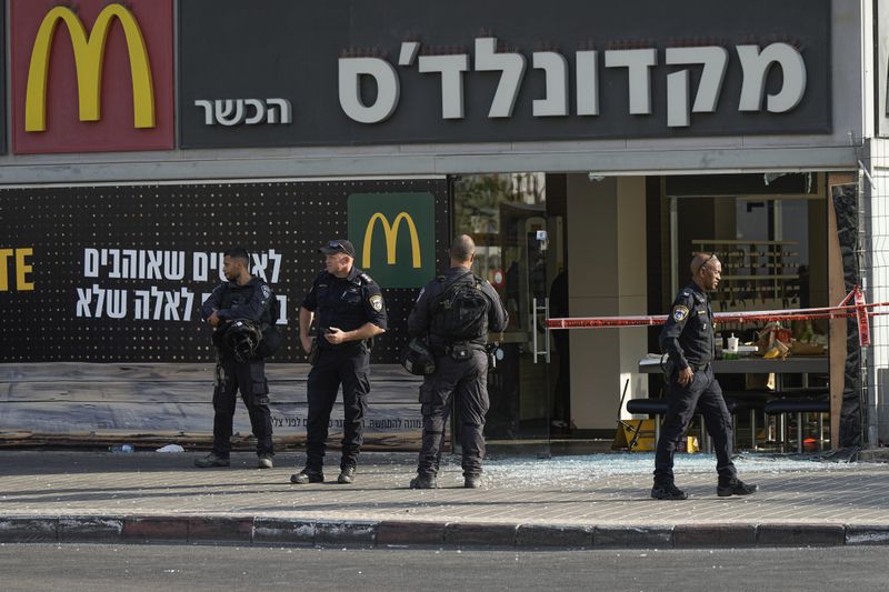 Police officers examine the scene of a stabbing and shooting attack where Israel's Magen David Adom rescue service said one person was killed and several others were wounded in Beersheba, Israel, Sunday, Oct. 6, 2024. (AP Photo/Tsafrir Abayov)