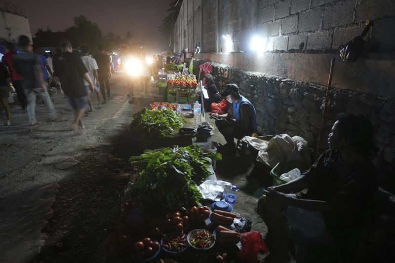 Vendors sell vegetables with battery supported lights at a market in Dili, East Timor Sunday, Sept. 8, 2024. (AP Photo/Firdia Lisnawati)