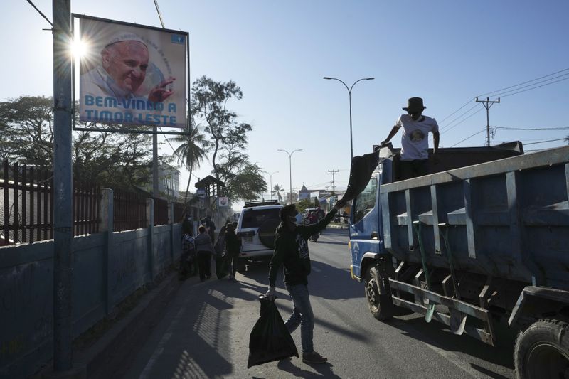 Workers clean up a street near a poster welcoming Pope Francis, in Dili, East Timor, Monday, Aug. 12, 2024. (AP Photo/Achmad Ibrahim)