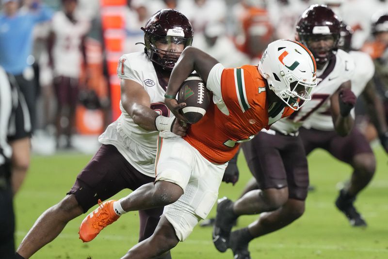 Virginia Tech defensive lineman Wilfried Pene (91) grabs Miami quarterback Cam Ward (1) during the first half of an NCAA college football game, Friday, Sept. 27, 2024, in Miami Gardens, Fla. (AP Photo/Marta Lavandier)