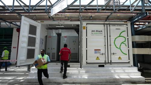 A worker walks in front of the 500-kilowatt battery energy storage system inside the Hindustan Coca-Cola Beverages factory in Thiruvallur district, on the outskirts of Chennai, India, Tuesday, July 16, 2024. (AP Photo/Mahesh Kumar A.)