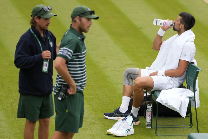 Novak Djokovic of Serbia sits in his chair as ground staff look on during a training session on Court 2 at the All England Lawn Tennis and Croquet Club in Wimbledon, London, Friday, June 28, 2024. The Wimbledon Championships begin on July 1. (AP Photo/Kirsty Wigglesworth)