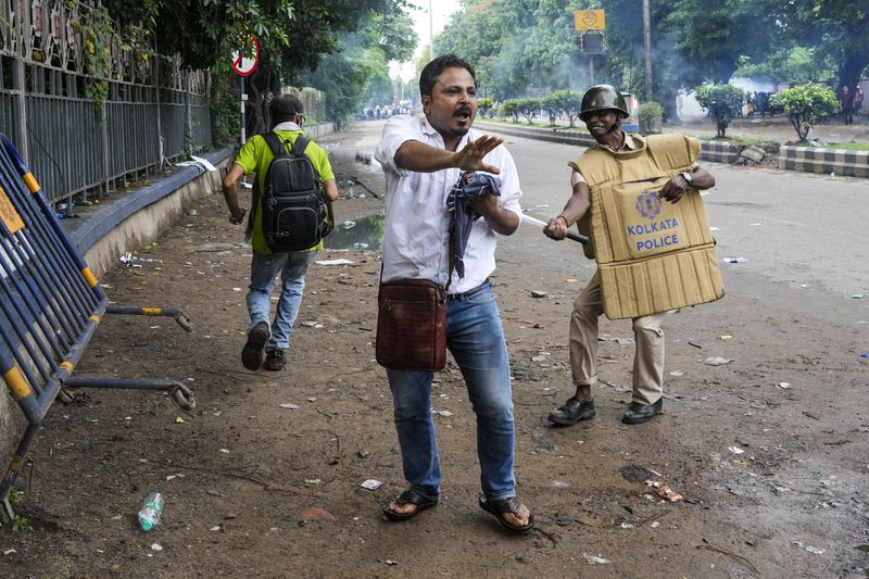 A policeman hits a protester, protesting against the rape and murder of a resident doctor at a government hospital earlier this month, in Kolkata, India, Tuesday, Aug. 27, 2024. (AP Photo/Bikas Das)