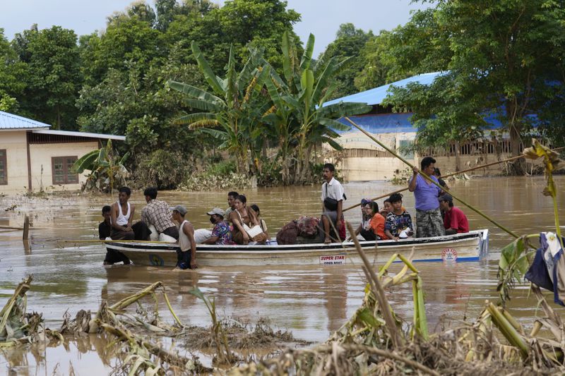 Local residents travel by boat on a flooded road, in Naypyitaw, Myanmar, Tuesday, Sept. 17, 2024. (AP Photo/Aung Shine Oo)