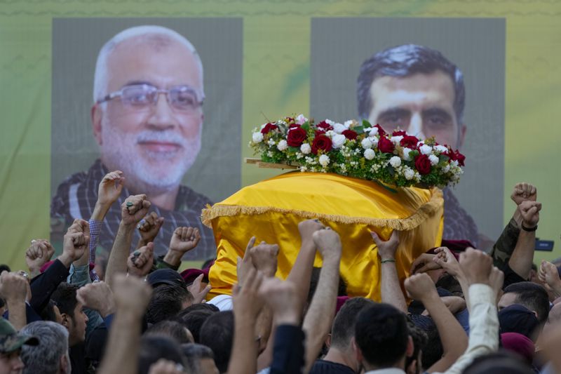 Hezbollah members carry the coffins of Hezbollah commanders Ibrahim Kobeisi, seen in the picture left, and Hussein Ezzedine, right, during their funeral procession in Beirut's southern suburb, Wednesday, Sept. 25, 2024. (AP Photo/Hassan Ammar)