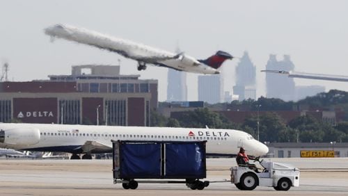 Delta jets pass behind a baggage handler at Hartsfield Jackson Atlanta International Airport. The U.S. Securities and Exchange Commission issued a subpoena to the city last week seeking documents about use of airport revenue and financial statements. Bob Andres / robert.andres@ajc.com