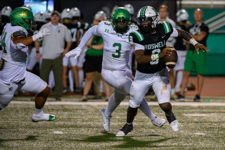 Roswell’s quarterback, Trey Smith, eludes Buford defenders. (Jamie Spaar for the Atlanta Journal Constitution)