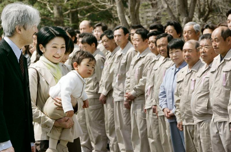 FILE - Japan's Prince Akishino, left, and his wife Princess Kiko, carrying their son Prince Hisahito, are welcomed by the staff of an imperial ranch in Takanezawa, north of Tokyo, March 28, 2008. (AP Photo/Koji Sasahara, File)