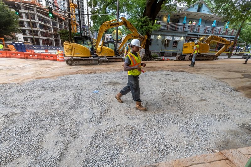 Workers continued to put the finishing touches on the filled in water main hole Wednesday morning, June 5, 2024 following the city’s announcement that water had been restored following the break on West Peachtree Street and 11th Street. The city said the system was being brought back online slowly to “allow system pressures to build.” (John Spink/AJC)