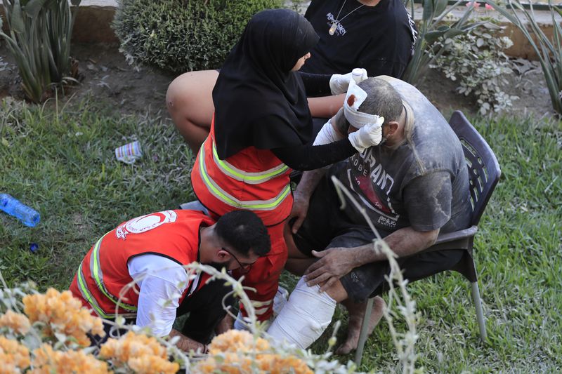 Paramedics treats a man who was injured after an Israeli airstrike hit two adjacent buildings east of the southern port city of Sidon, Lebanon, Sunday, Sept. 29, 2024. (AP Photo/Mohammed Zaatari)