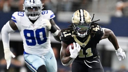 New Orleans Saints running back Alvin Kamara (41) breaks away with Dallas Cowboys defensive end DeMarcus Lawrence (90) in tow while running for a long touchdown during the first half of an NFL football game, Sunday, Sept. 15, 2024, in Arlington, Texas. (AP Photo/Tony Gutierrez)