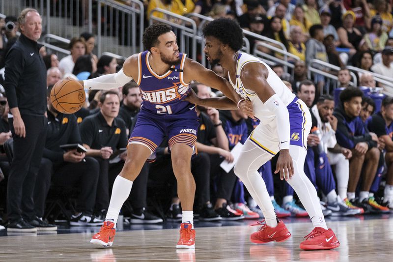 Phoenix Suns guard Tyus Jones (21) dribbles under pressure from Los Angeles Lakers guard Bronny James (9) during the first half of a preseason NBA basketball game Sunday, Oct. 6, 2024, in Palm Desert, Calif. (AP Photo/William Liang)