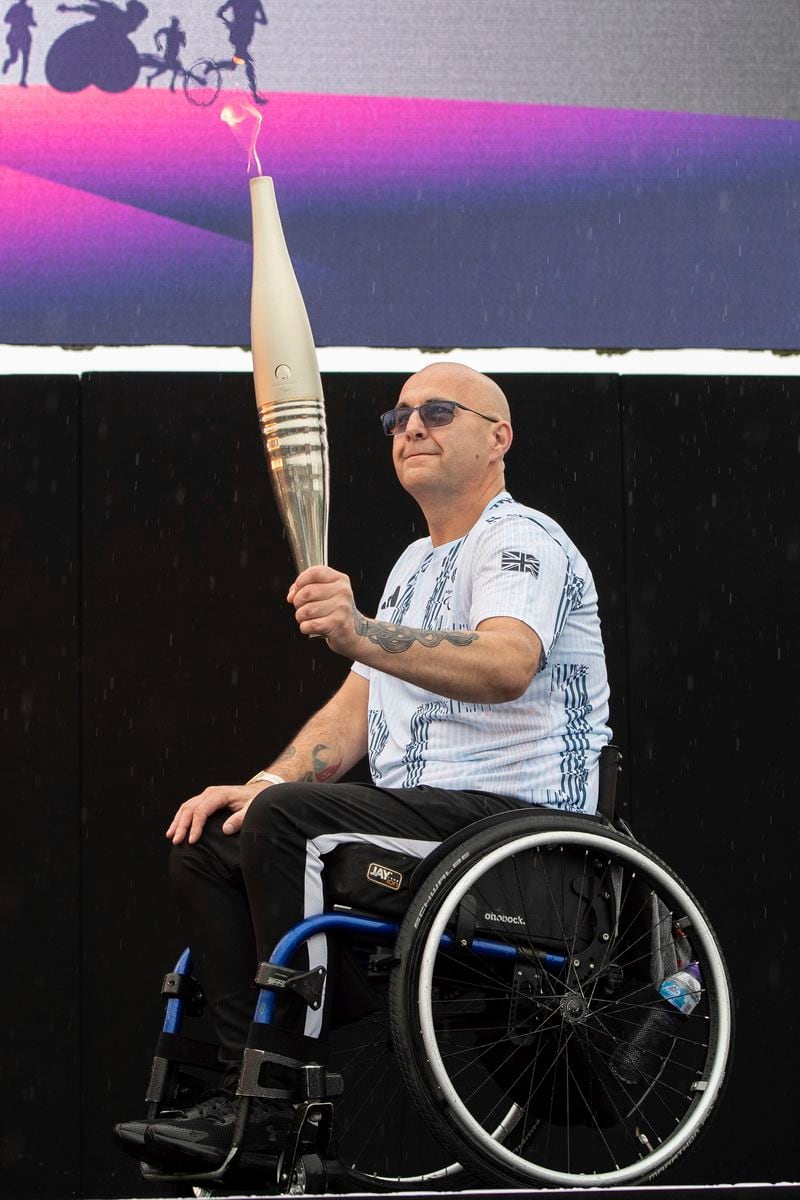 British Paralympian Gregor Ewan holds the Paralympic Torch during the flame lighting ceremony in Stoke Mandeville, widely considered the birthplace of the Paralympic Games, England, Saturday, Aug. 24, 2024. (AP Photo/Thomas Krych)