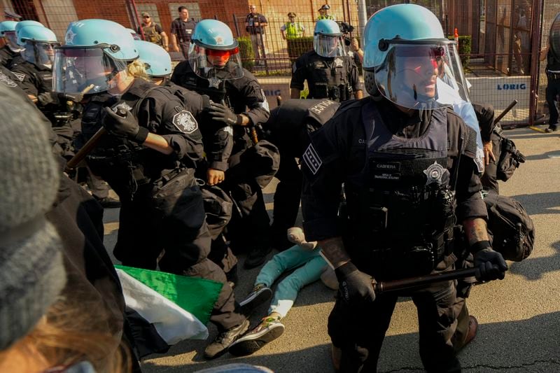 Police take a protester into custody after a fence surrounding United Center was knock down at the Democratic National Convention Monday, Aug. 19, 2024, in Chicago. (AP Photo/Julio Cortez)