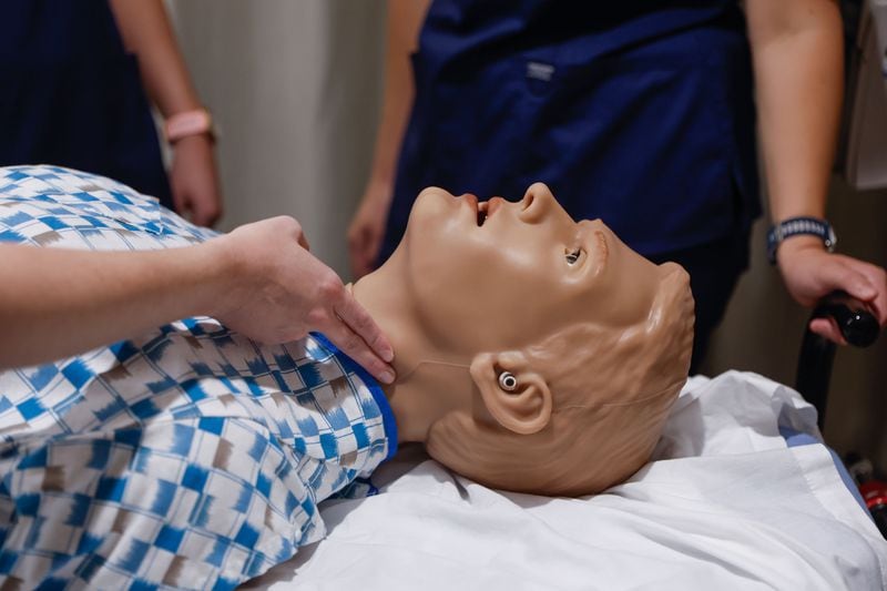 Emory University distance-accelerated nursing students check the pulse of an AI-equipped patient simulator at the Emory Nursing Learning Center on Wednesday, Aug. 7, 2024. (Natrice Miller/ AJC)