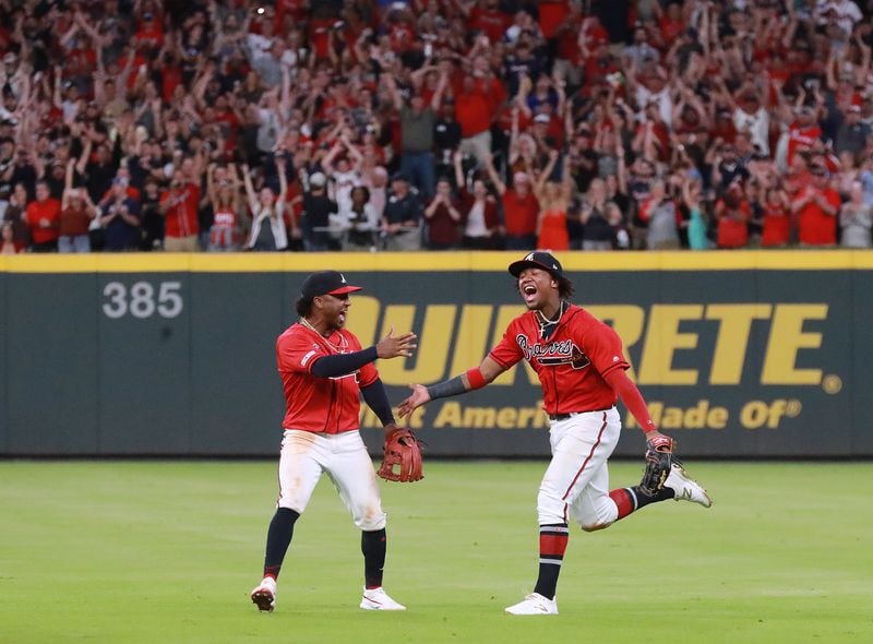 Ozzie Albies (left), Ronald Acuna (right) and Braves fans celebrate after Acuna Jr. caught a fly ball for the last out.  Curtis Compton/ccompton@ajc.com