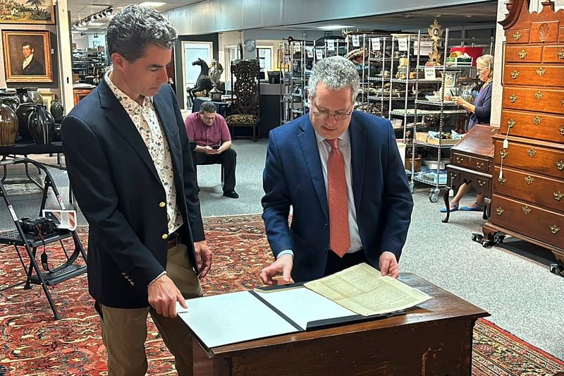 Auctioneer Andrew Bruck, left, and historian Seth Kaller, right show off a 1787 copy of the U.S. Constitution that will be put up for auction on Sept. 28, 2024 at Bruck Auctions in Asheville, N.C., on Thursday, Sept. 5. (AP Photo/Jeffrey Collins)