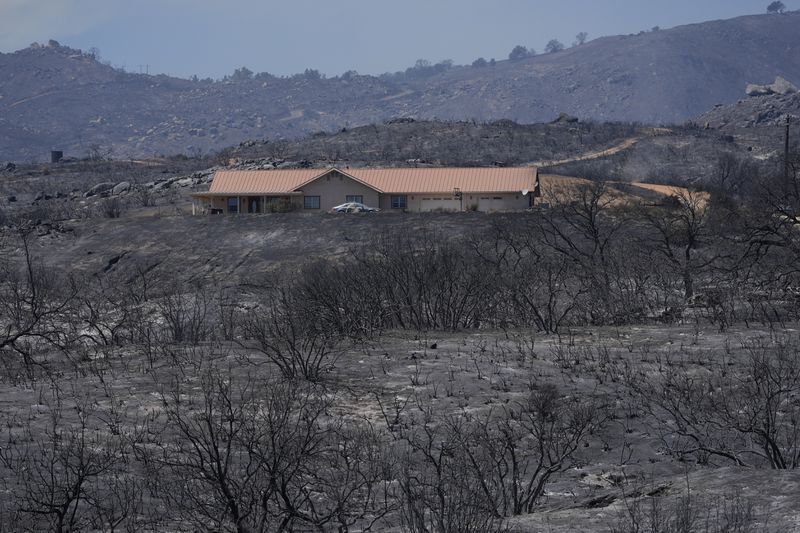 A fire-ravaged landscape surrounds a property after the Airport Fire swept through Wednesday, Sept. 11, 2024, in El Cariso Village, in unincorporated Riverside, County, Calif. (AP Photo/Gregory Bull)