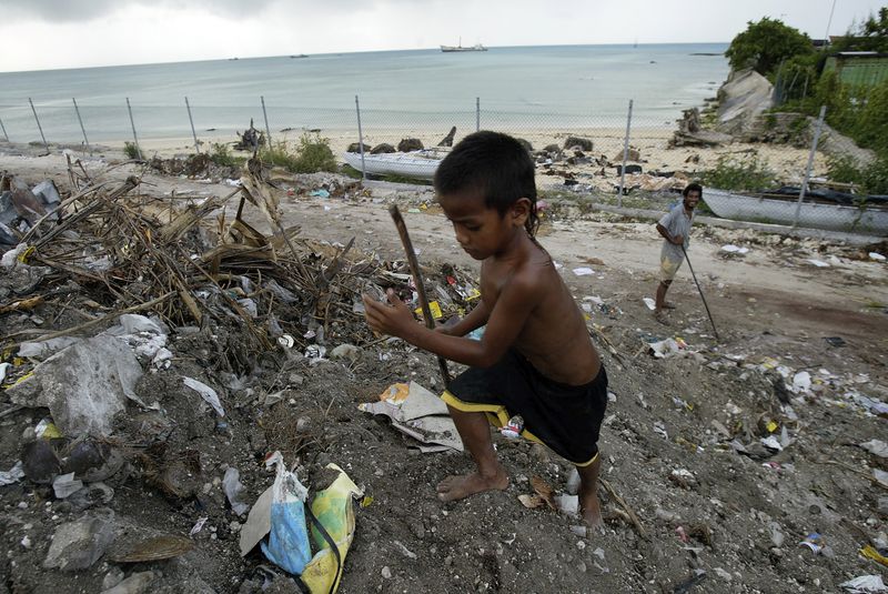 FILE - A boy scavenges for useful items at Red Beach dump on Tarawa atoll, Kiribati, on March 30, 2004. (AP Photo/Richard Vogel, File)