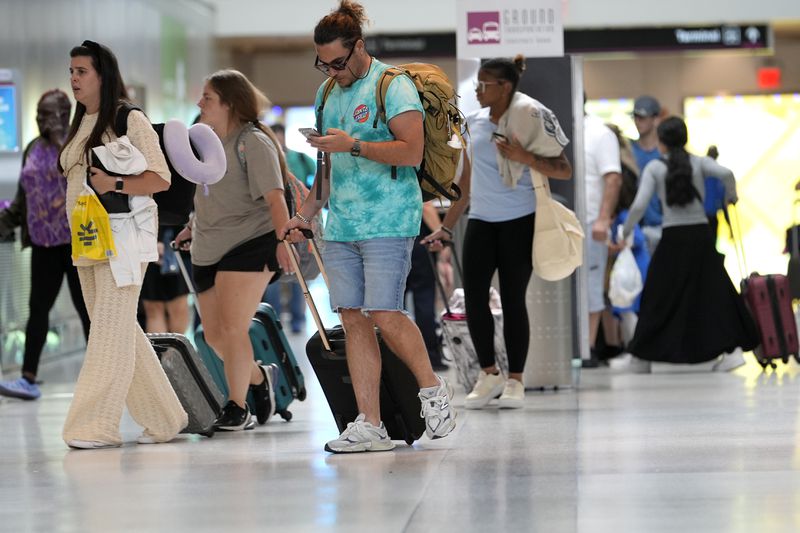 Travelers walk through Miami International Airport, Wednesday, July 3, 2024, in Miami. (AP Photo/Lynne Sladky)