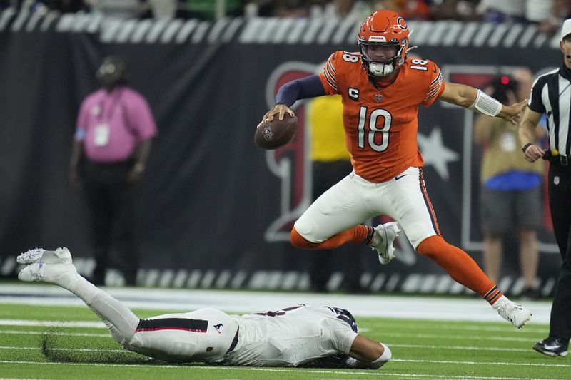 Chicago Bears quarterback Caleb Williams (18) leaps over Houston Texans safety Jalen Pitre to avoid a sack during the first half of an NFL football game Sunday, Sept. 15, 2024, in Houston. (AP Photo/Eric Christian Smith)