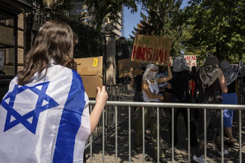 A pro-Israel student holds a sign while pro-Palestinian supporter hold picket line outside Barnard College, Tuesday, Sept. 3, 2024, in New York. (AP Photo/Yuki Iwamura)