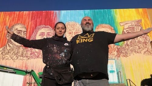 Yehimi Cambrón (left) and fellow muralist Joe Dreher stand outside Cambron's new mural, "Mi Gente," which Dreher helped paint. CONTRIBUTED: ATLANTA HISTORY CENTER