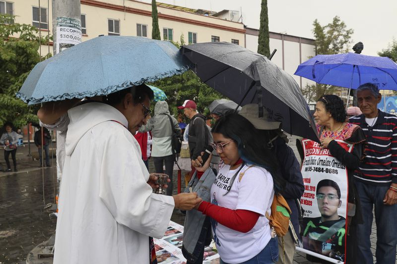 Anglican priest Rev. Arturo Carrasco gives communion to Janet Piña Montelongo during a Catholic Mass commemorating the missing of the search collective "Uniendo Esperanzas" or Uniting Hope, in Mexico City, Sunday, July 21, 2024. Piña's father Rafael went missing when he did not return home from work in 2021. (AP Photo/Ginnette Riquelme)