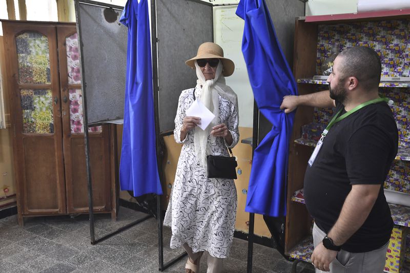 A voter prepares to cast her ballot inside a polling station during the presidential elections, Saturday, Sept. 7, 2024, in Algiers, Algeria. (AP Photo/Fateh Guidoum)