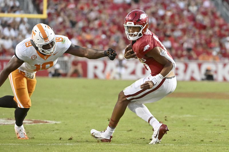 Arkansas quarterback Taylen Green (10) spins away from Tennessee defensive lineman Joshua Josephs (19) as he scrambles out fo the pocket during the first half of an NCAA college football game, Saturday, Oct. 5, 2024, in Fayetteville, Ark. (AP Photo/Michael Woods)